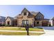 Attractive stone and brick home with a covered porch, two-car garage, landscaped yard, and clear blue sky at 4287 Prairie Falcon Dr, Zionsville, IN 46077