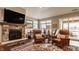 Inviting living room showcasing a stone fireplace, mounted TV, comfortable seating, and serene outdoor views at 4287 Prairie Falcon Dr, Zionsville, IN 46077