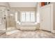 Elegant bathroom featuring a glass enclosed shower and a large soaking tub under a bright window at 438 E Vermont St, Indianapolis, IN 46202
