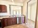 Well-lit kitchen area with double sink, stainless steel dishwasher, and view into living room at 4889 Lilium Dr, Plainfield, IN 46168