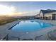 An outdoor swimming pool with lounge chairs and tables set against the backdrop of a suburban community during a beautiful sunset at 4889 Lilium Dr, Plainfield, IN 46168