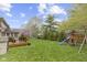 Large backyard featuring a deck, lush lawn, mature trees, and a playset with a slide and swings at 4978 St Charles Pl, Carmel, IN 46033