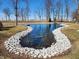 Serene pond with natural rock edging, framed by mature trees and expansive green lawn at 551 E 600 S, Lebanon, IN 46052