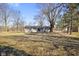 Backyard featuring the exterior of the house with a patio and a large grassy area surrounded by mature trees at 6603 Iona Rd, Indianapolis, IN 46203
