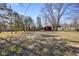 Large backyard with mature trees, a red barn, and an open space, perfect for outdoor activities at 6603 Iona Rd, Indianapolis, IN 46203