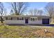Well-maintained single-story home featuring a gray brick exterior, attached garage, and tidy landscaping at 6603 Iona Rd, Indianapolis, IN 46203