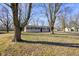Cozy single-story home boasts a well-kept lawn and inviting gray brick facade surrounded by mature trees at 6603 Iona Rd, Indianapolis, IN 46203