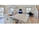 Modern kitchen island with a sink, white countertops, and an open view into the living area at 7256 Firestone Rd, Whitestown, IN 46075