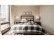 Bright bedroom featuring a cozy bed with plaid comforter, bedside tables with lamps, and a comfortable bench at 802 N Meridian St # 103, Indianapolis, IN 46204