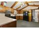 Traditional kitchen with wooden cabinets, black appliances, and beamed ceiling at 8172 S Shoreview Dr, Trafalgar, IN 46181