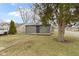 View of a one-story home with gray siding, a concrete porch and a well-maintained lawn and trees at 1159 S Bradley Ave, Indianapolis, IN 46203