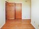 Bedroom with hardwood floors, yellow walls, and an open closet with wood doors at 1310 Bowman Dr, Greenfield, IN 46140