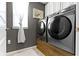 Modern laundry room equipped with gray front load washer and dryer and natural light at 13615 Moorcroft Dr, Fishers, IN 46037