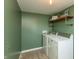 Neat laundry room features a washer, a dryer, a utility shelf, light green walls, and tile flooring at 1718 Gilmore St, Columbus, IN 47201