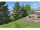 Landscaped backyard with lush lawn, mature trees, and a stone patio with a cozy fire pit at 2750 Joshua Dr, Carmel, IN 46033