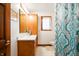 Bright bathroom with a light wood vanity, framed mirror, decorative shower curtain and window with white curtains at 3949 W 250 N, Anderson, IN 46011