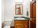 Well lit bathroom featuring wood vanity, mirror, toilet, and light fixtures; door to another room visible in mirror at 3949 W 250 N, Anderson, IN 46011