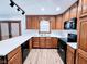 Kitchen with wood cabinets, white countertops, black appliances, and modern track lighting at 4109 E Epler Ave, Indianapolis, IN 46237