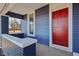 A charming covered porch with a vibrant red door, showcasing a cozy and inviting entryway with blue siding at 4844 N 700 W, McCordsville, IN 46055