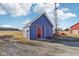 Blue shed with a red door and a windmill feature an empty field under partly cloudy skies at 4844 N 700 W, McCordsville, IN 46055