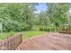 A well-manicured backyard with a wooden deck, lush grass, and mature trees at 5014 Melbourne Rd, Indianapolis, IN 46228