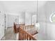 Hallway with hardwood floors, wooden banister, decorative light fixture, and natural light at 5014 Melbourne Rd, Indianapolis, IN 46228