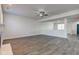 Open-concept living room with gray hardwood floors, fireplace and ceiling fan at 5402 Basin Park Dr, Indianapolis, IN 46239