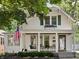 Charming two-story home featuring a covered front porch, swing, and an American flag at 5426 Broadway St, Indianapolis, IN 46220