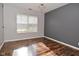 Large window and chandelier in this bedroom with a gray accent wall and hardwood floors at 5855 Dapple Trce, Indianapolis, IN 46228