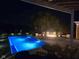 Night view of a private pool with blue lighting, lounge chairs by a fire pit, and landscaping at 7152 Old Morgantown Rd, Martinsville, IN 46151