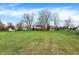 Expansive backyard featuring a well-maintained lawn, mature trees, and neighborhood homes in the distance at 7344 Monon Cir, Indianapolis, IN 46256