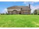 Spacious backyard featuring a well-maintained lawn, brick accents, and a covered patio area at 7357 Windridge Way, Brownsburg, IN 46112