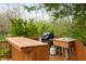 Outdoor wooden kitchen with a built-in bar, grill, sink, and scenic backyard views at 12512 Geist Cove Dr, Indianapolis, IN 46236