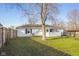 A view of the backyard, showing the fence line, mature tree, and sunroom at 1319 Brookside Dr, Columbus, IN 47201