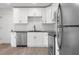 Modern kitchen featuring white cabinets, subway tile backsplash, stainless steel appliances, and wood-look flooring at 1319 Brookside Dr, Columbus, IN 47201