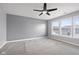 This bedroom features neutral carpet, gray walls, three windows that let in plenty of natural light, and a ceiling fan at 2016 Woodland Parks Dr, Columbus, IN 47201