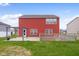 View of the two-story home's exterior with a vibrant red facade, complemented by well-maintained landscaping and backyard at 2016 Woodland Parks Dr, Columbus, IN 47201