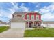 Charming two-story red home featuring a stone facade and well-manicured lawn at 2016 Woodland Parks Dr, Columbus, IN 47201