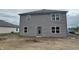 Rear view of a two-story home with gray siding and windows, featuring a door leading to the backyard at 3328 Stafford St, Sheridan, IN 46069