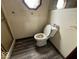 Cozy bathroom with wood-look flooring, toilet, and window, providing a private and functional space at 4534 N State Road 9, Anderson, IN 46012