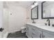 Bathroom featuring a grey double vanity with black fixtures, complemented by a marble tiled shower at 5004 Boardwalk Pl, Indianapolis, IN 46220
