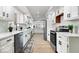 Galley kitchen with white cabinetry, stainless steel appliances, and wood-look floors throughout at 5004 Boardwalk Pl, Indianapolis, IN 46220