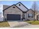 Charming two-story home featuring a grey brick facade, dark trim, a manicured lawn, and a two-car garage at 553 Farnham Dr, Westfield, IN 46074