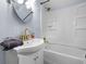 Bathroom with a white vanity, sink, modern gold faucet, round mirror, and tiled shower and bath at 721 E Morris St, Indianapolis, IN 46203
