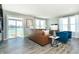 Bright living room with a leather sofa, blue chairs, and a sliding door to a patio overlooking the water at 7572 Bluegill Dr, Noblesville, IN 46062