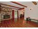 Cozy living room with exposed beams, wood-look floors, and brick fireplace, adjacent to the dining area at 8172 Shottery Ter, Indianapolis, IN 46268