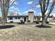 Charming single-story home featuring a prominent stone chimney and mature trees, set in a well-kept front yard at 8795 Carrollton Ave, Indianapolis, IN 46240