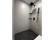 Modern shower with black shower head, matte grey tile and black and white patterned floor at 8795 Carrollton Ave, Indianapolis, IN 46240