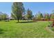 Spacious backyard featuring lush green grass, mature trees, and playground at 10576 Greenway Dr, Fishers, IN 46037