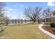 Large grass backyard leading to lake with mature trees and concrete walkway at 10817 Lakeview Dr, Carmel, IN 46033